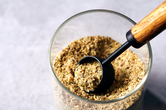 Scoop of Bloom Boost fiber and seed blend — a whole-food mix of chia, flax, oat bran, psyllium, pumpkin seed powder, and hemp hearts for gut health